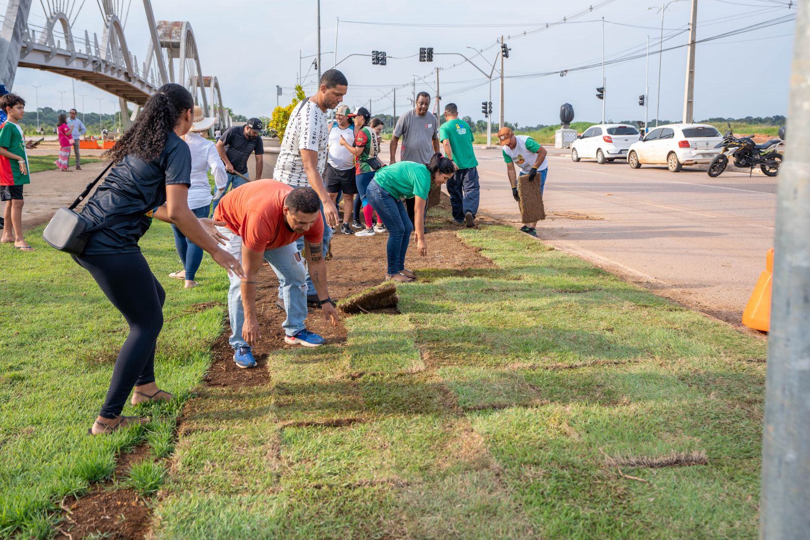 Voluntários realizam o plantio de grama no entorno da passarela do Espaço Alternativo